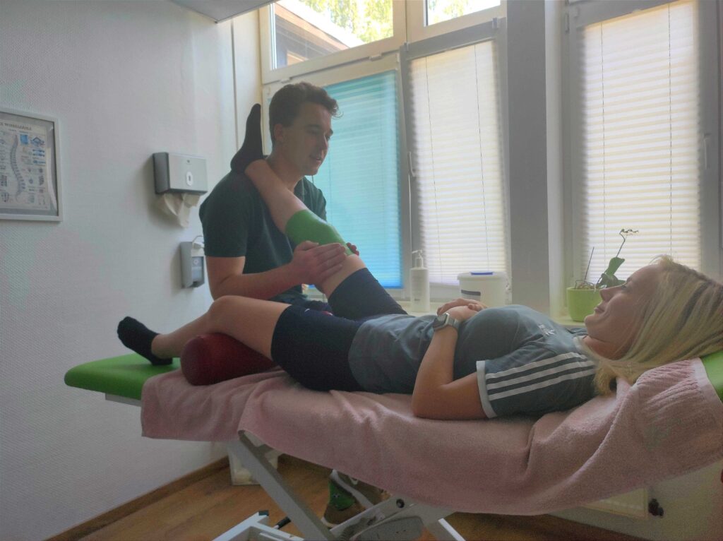 Kinesiotaping Knie; Phil behanddelt eine Patientin auf einer Massageliege